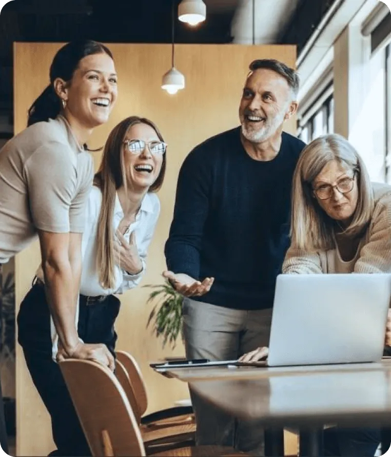 A happy group gathered around a laptop, sharing a moment of joy.